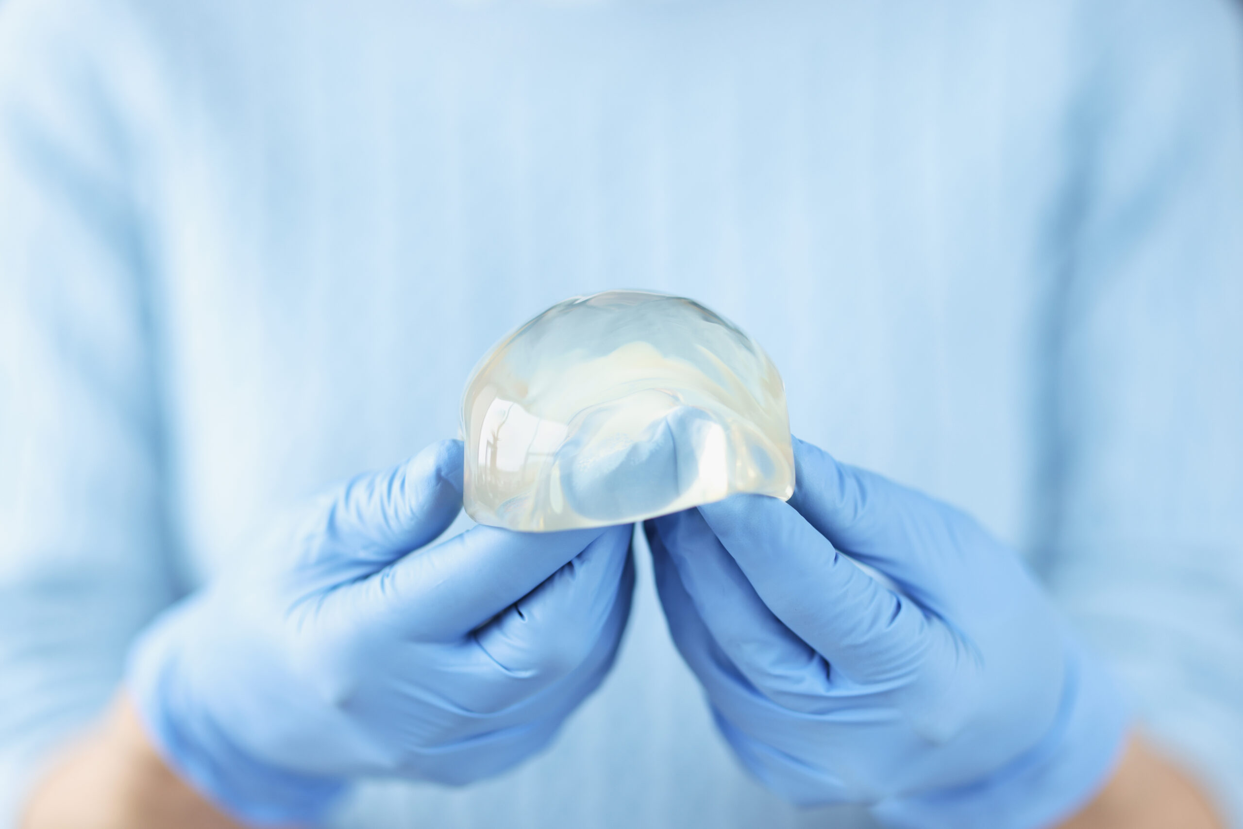 Silicone breast implant in hands of doctor. Breast augmentation plastic surgery concept